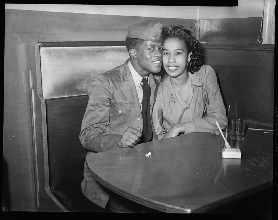 Man in military uniform and woman seated in booth
