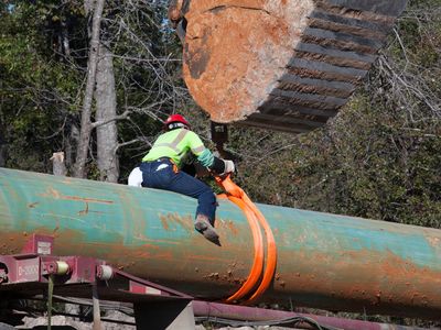 A worker unloads pipe from a truck during construction of the southern portion of the Keystone XL pipeline.