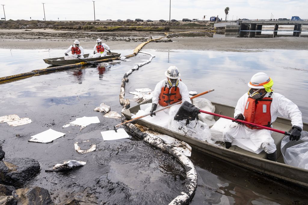 Workers with Patriot Environmental Services mop up oil on the surface of the water at Talbert Marsh in Huntington Beach, CA on Monday, October 4, 2021.