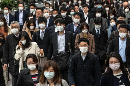 Commuters wearing face masks walk to work in Tokyo on April 7.