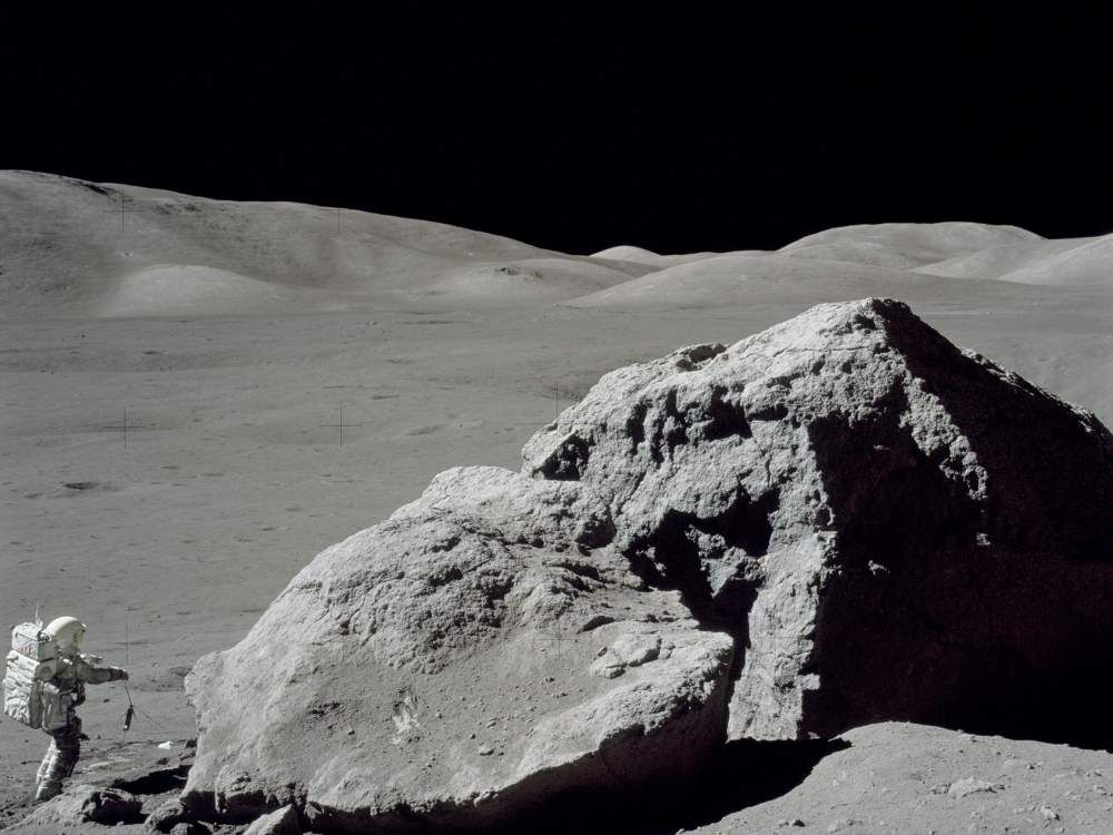 Jack Schmitt picking up the gnomon after collecting samples. This view is to the west toward the Lee Lincoln Scarp. Apollo image AS17-140-21496.