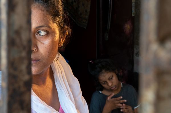 A Mother looking through Window with her physically disabled child in the background thumbnail