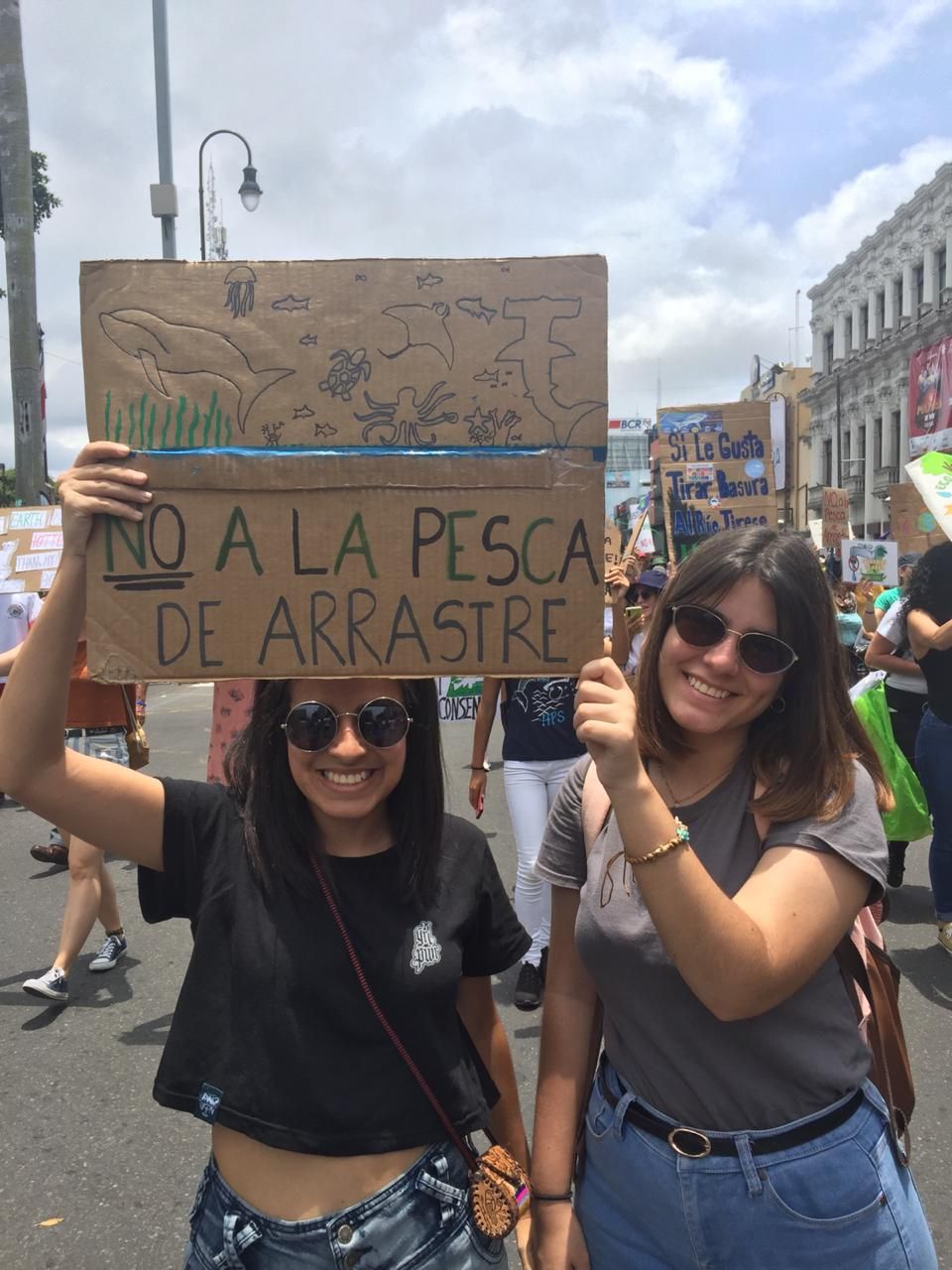 dos mujeres jóvenes con un cartel para salvar la vida del océano