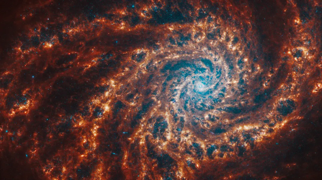 a spiral galaxy with deep red arms and dark cavities among the gas winding outward