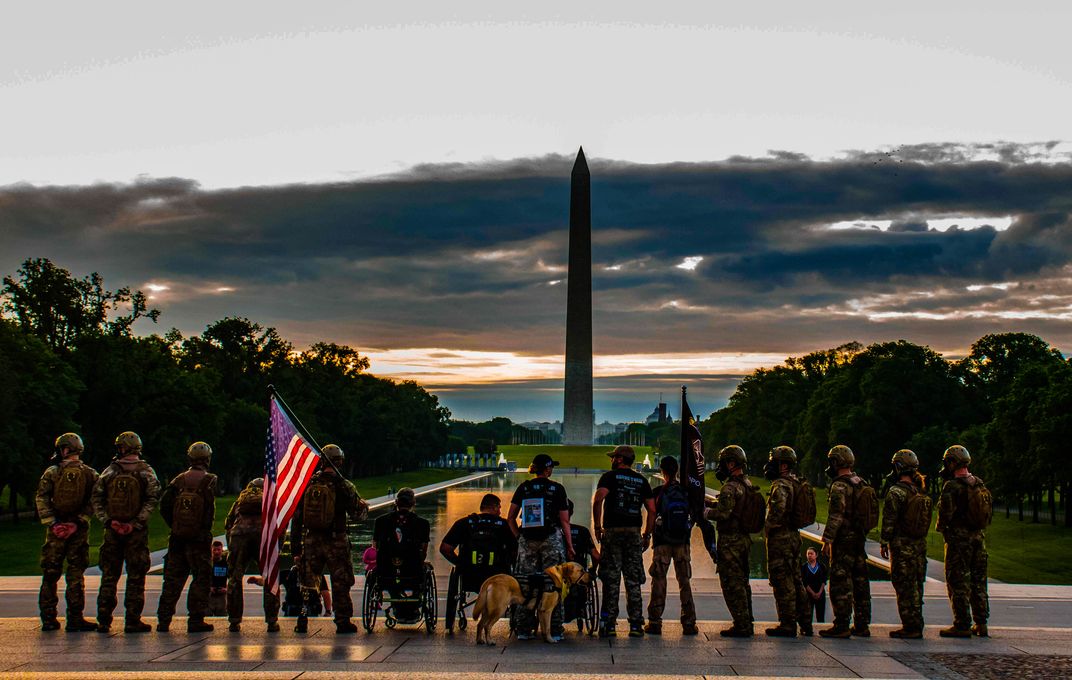 a group of former members stand in line with the Washington Monument in the distance