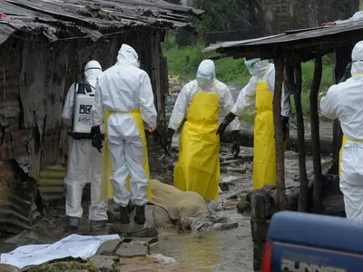 Health workers wearing protective clothing prepare to carry an abandoned dead body presenting with Ebola symptoms at Duwala market in Monrovia August 17, 2014.