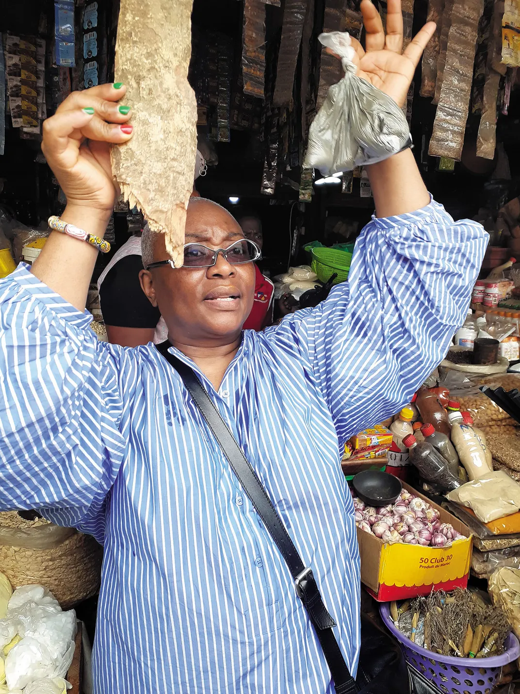 At a market in Douala, Cameroon, Brown holds up garlic bark and bongo spice, local ingredients used to season a variety of African dishes.