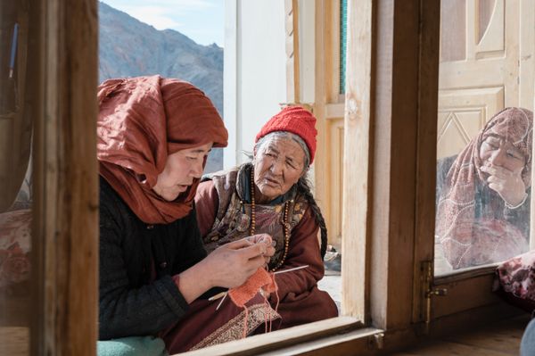 Three women drink tea while one knits. thumbnail