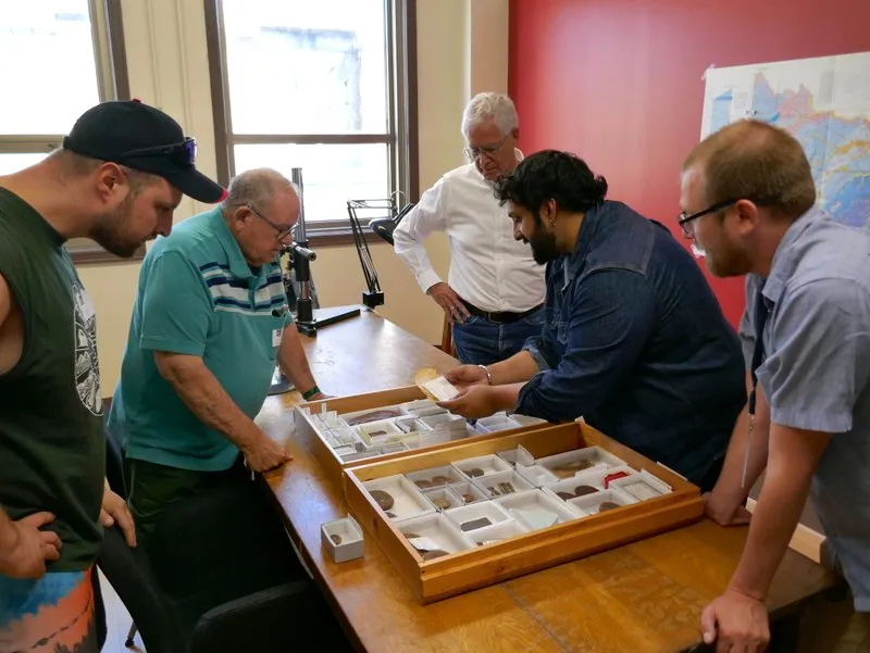 five people stand around a table with fossils in a case