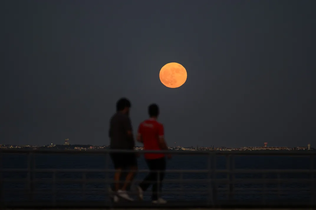 Strawberry moon peeks over the horizon in the sky across Lisbon, Portugal, on June 29, 2026