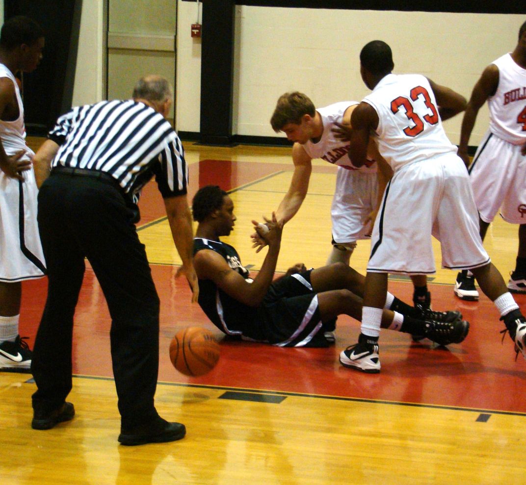 boy-helping-an-opposing-teamate-off-the-floor-after-a-collision-of-the