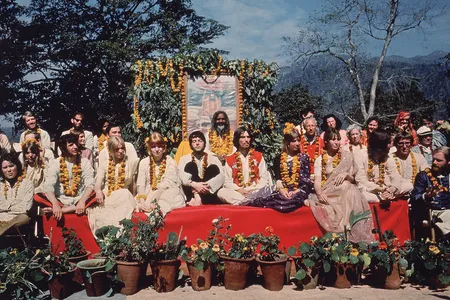 John Lennon chats with Mike Love (far right, in dark blue) as the Beatles sit for a photo with Maharishi and other course participants.