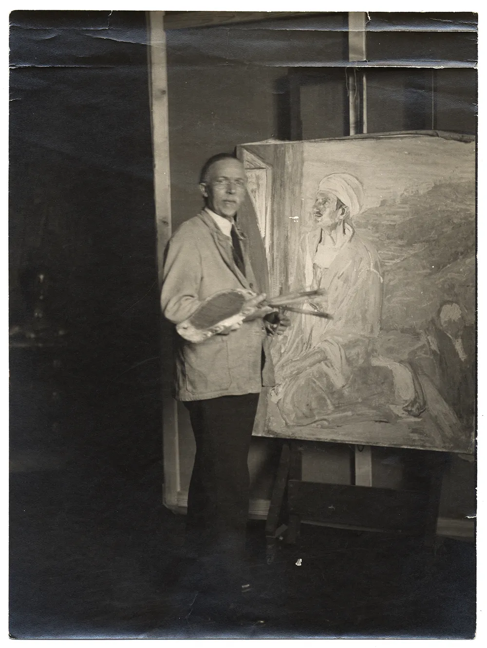 Henry Tanner in his studio next to his painting Judas.