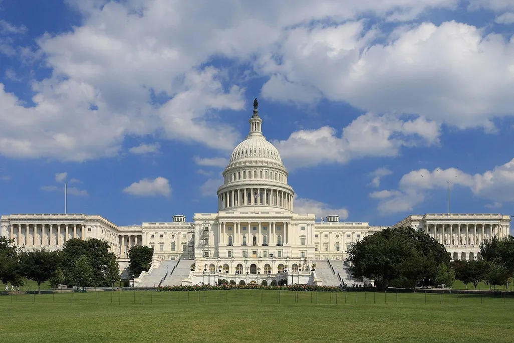 The US Capitol building, pictured on a bright sunny day with blue sky and white fluffy clouds behind