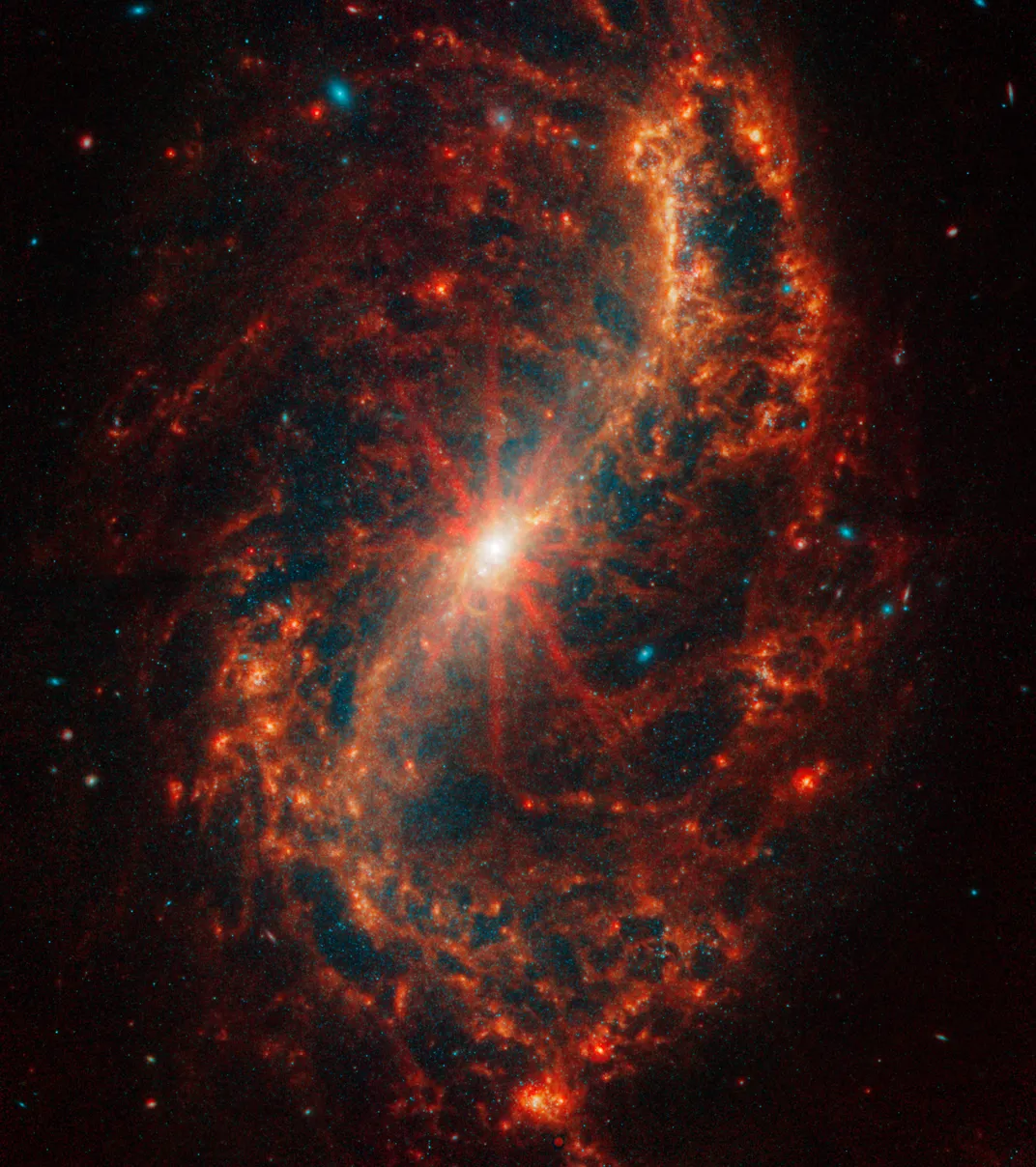 a spiral galaxy in red with some bright diffraction spikes coming from its glowing white center