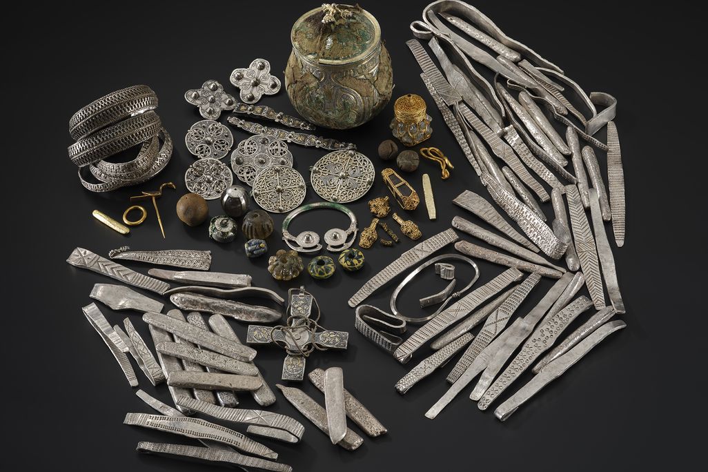 A group of gold, silver and other artifacts against a black background