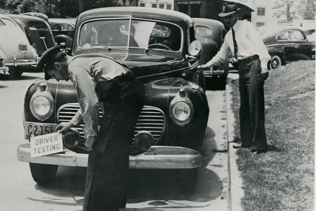 An examiner affixes a “driver testing” notice ahead of a road test in South Carolina