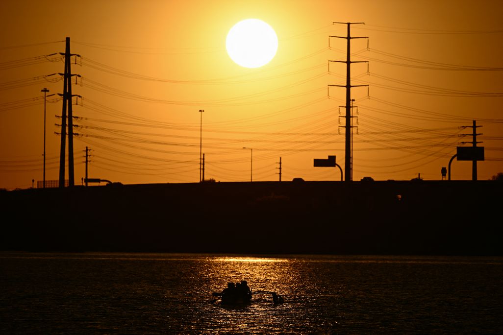 sun sets behind power lines in an orange sky