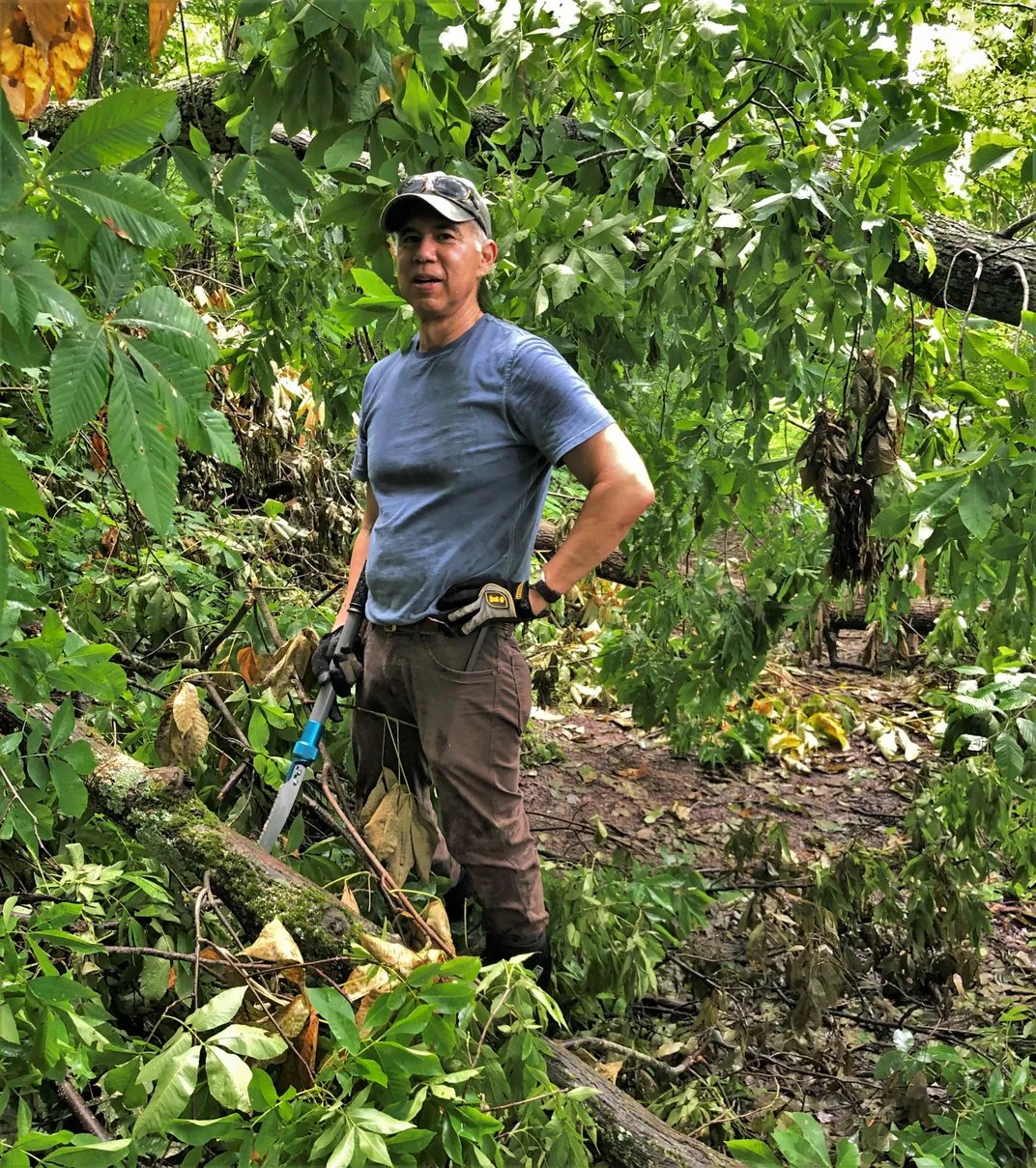 A person holding hedge trimmers near trees