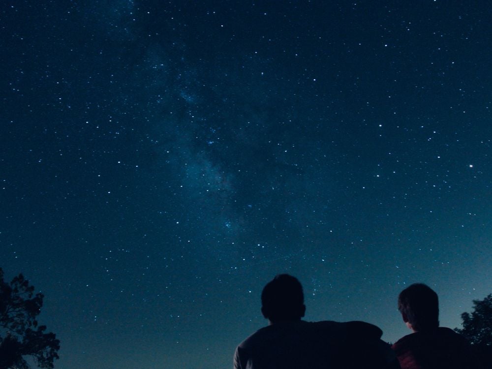 A pair of silhouetted people stargaze