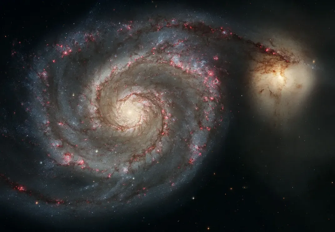 A large spiral galaxy beside a smaller elliptical galaxy
