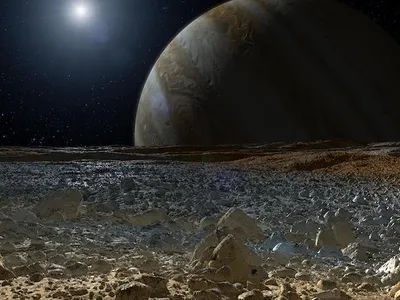 An artist&#39;s concept of a simulated view from the rough, icy surface of the moon Europa with Jupiter looming over the horizon.