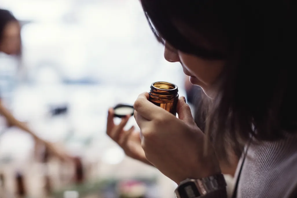 Woman smells open bottle close to her nose
