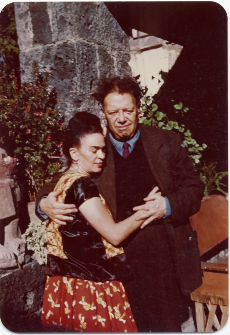 Kahlo and Rivera hugging and squinting in bright sunlight, outdoors