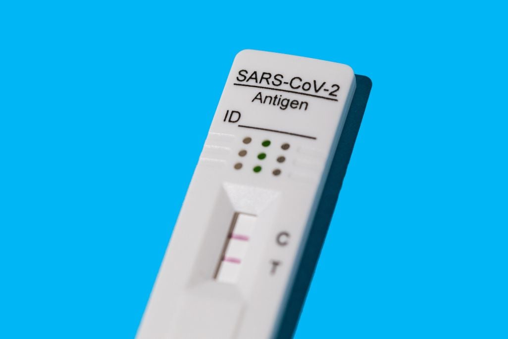 An image of a positive Covid-19 antigen test on a blue background