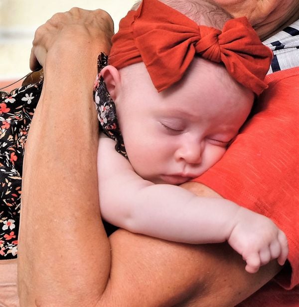 Baby sleeping in its grandmother's arms thumbnail