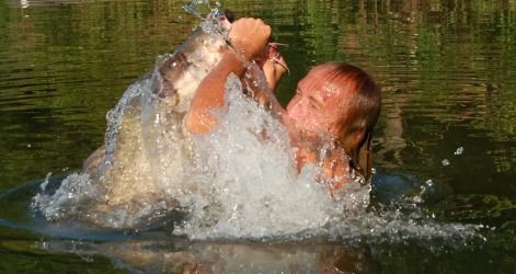 David Baggett, famed among noodlers, explodes from the water with a giant catfish in his hands.