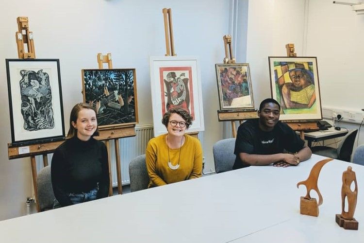 The researchers pose in front of paintings