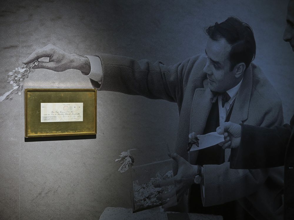 A receipt for one of Yves Klein's conceptual art pieces hangs on a wall atop a photo of the artist throwing gold into the Seine