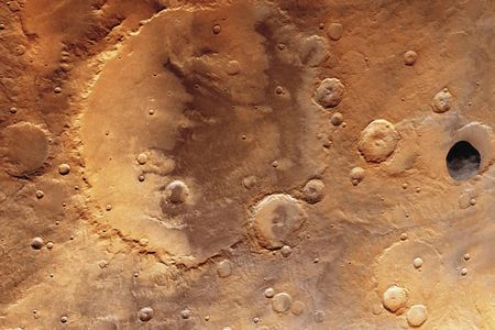 The dark gray object lurking above the Herschel crater on Mars is the Martian moon Phobos, as seen by the Viking Orbiter 1 in 1977