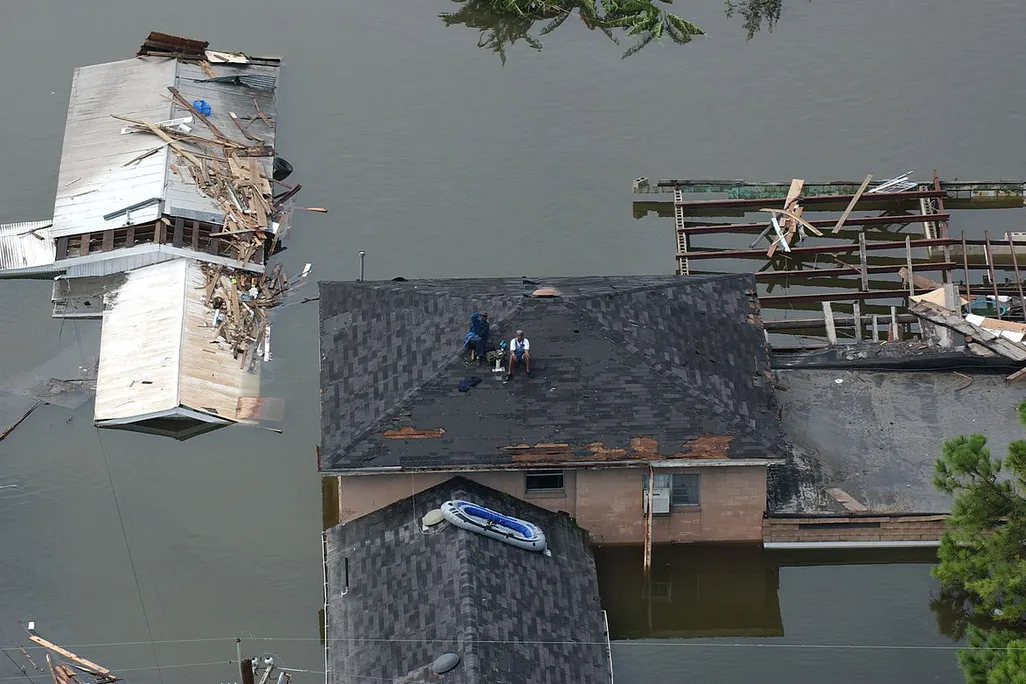 People sit on a roof waiting to be rescued after Hurricane Katrina