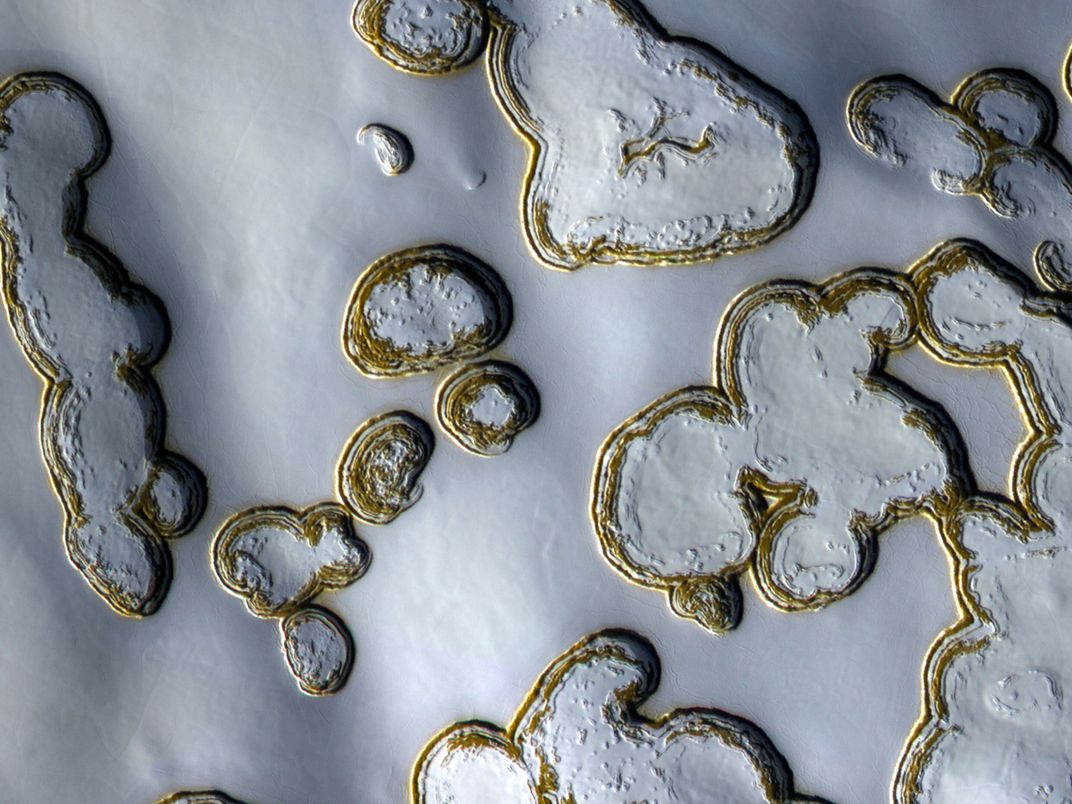 yellow rounded walls of pits against a blanket of ice