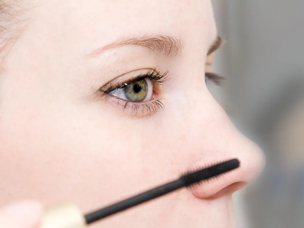 A woman applying mascara to her eyes