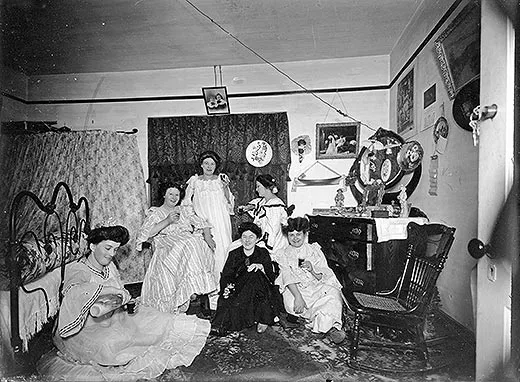 Women posed together with drinks in hand in bedroom