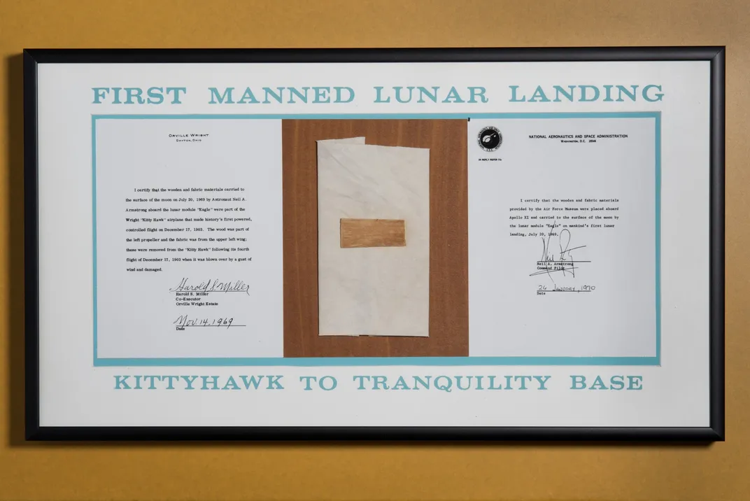 wood, fabric and two letters of authenticity in display case labeled "First manned lunar landing Kitty Hawk to Tranquility Base"