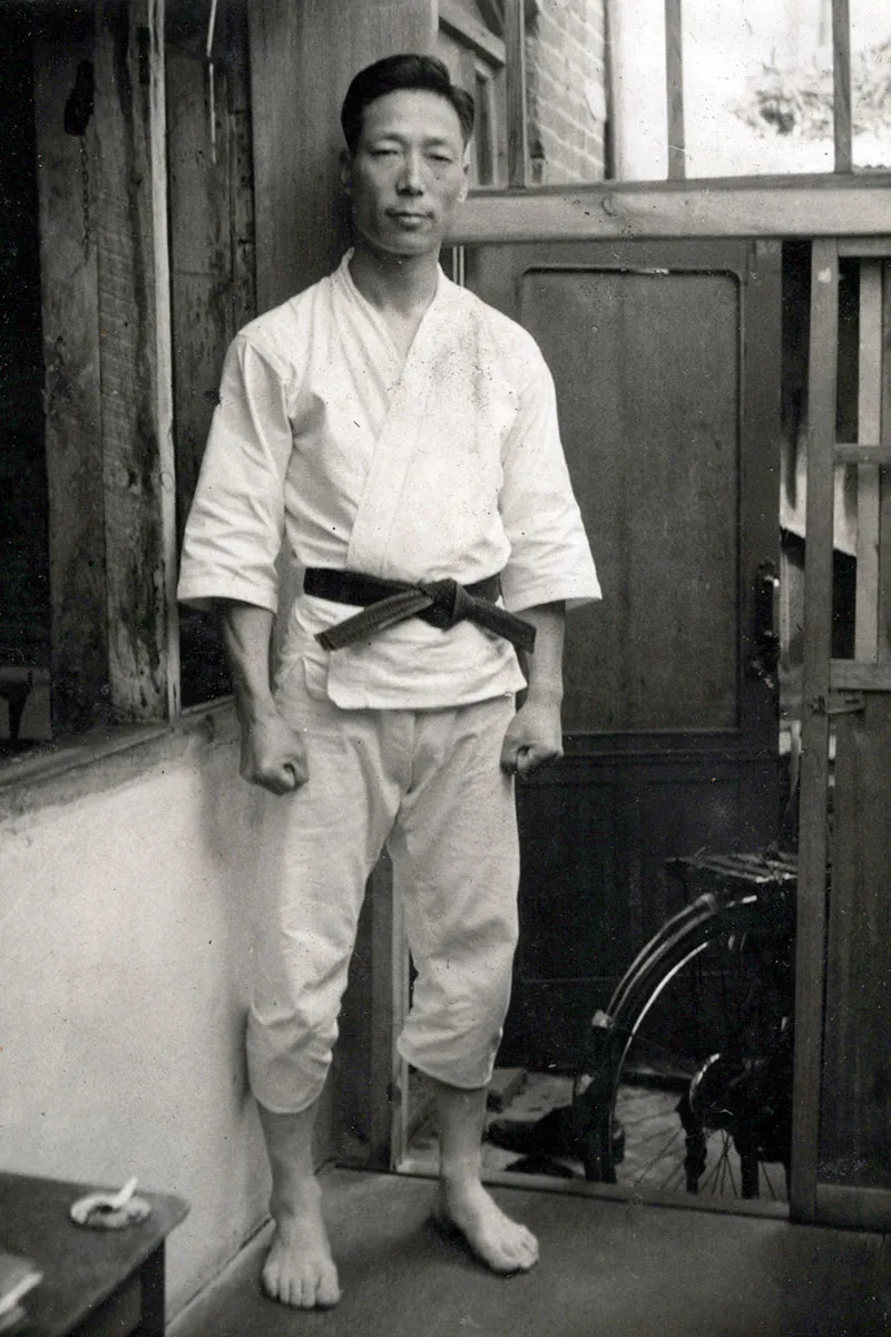 Grand Master Kim stands in his uniform and looks at the camera. The image is in black and white.