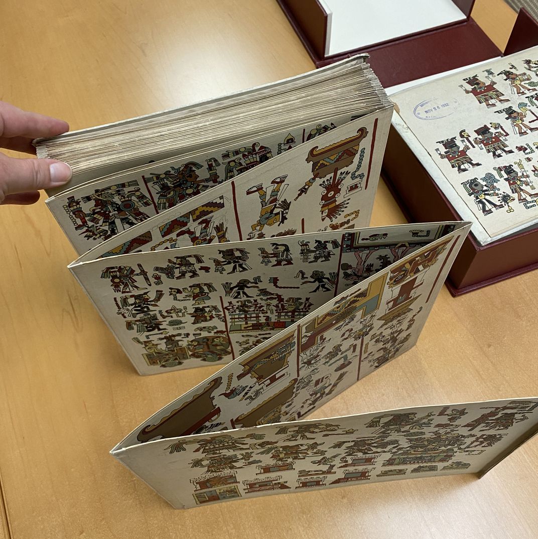 Early 20th century reproduction of a Mixtec codex, opened on table to show accordion shape.