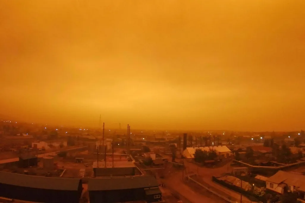 A photo of a small town in Russia. Its skies glowing an eerie amber color as wildfires continue to rage in Yakutia. 