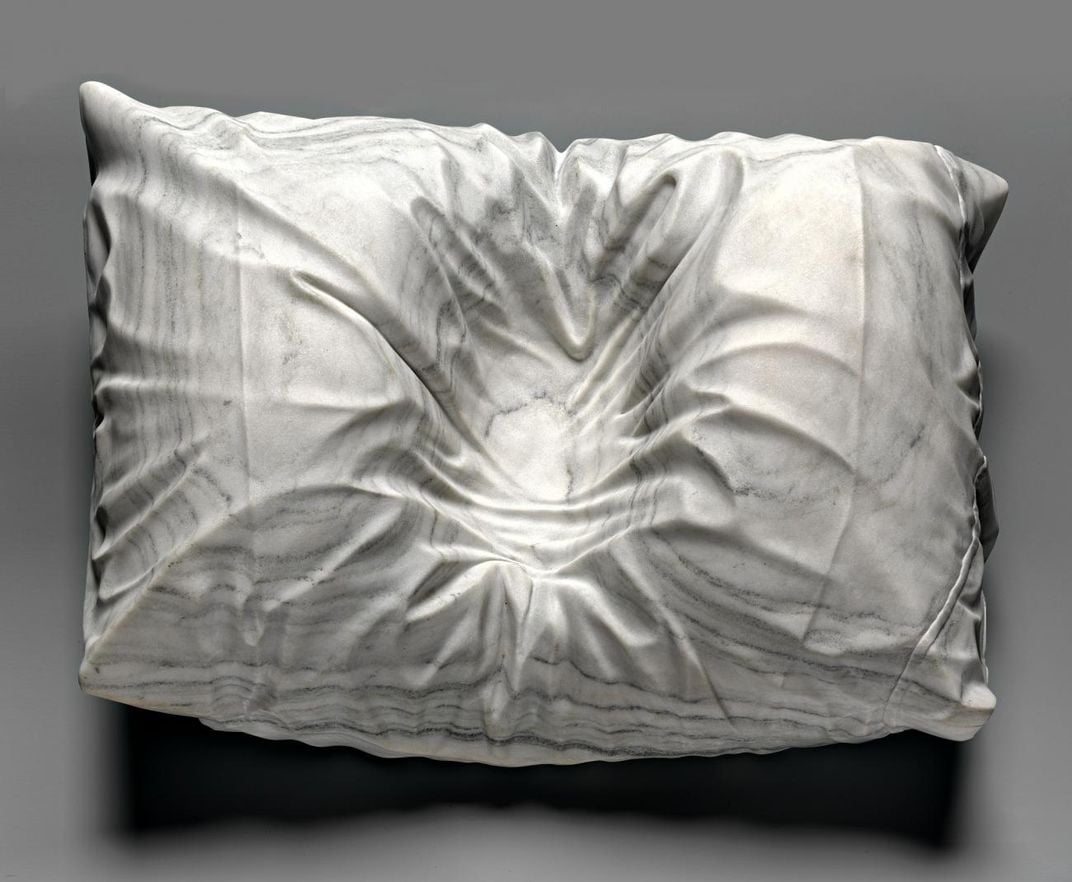 A photograph of a marble pillowcase with an indention where a head was. 