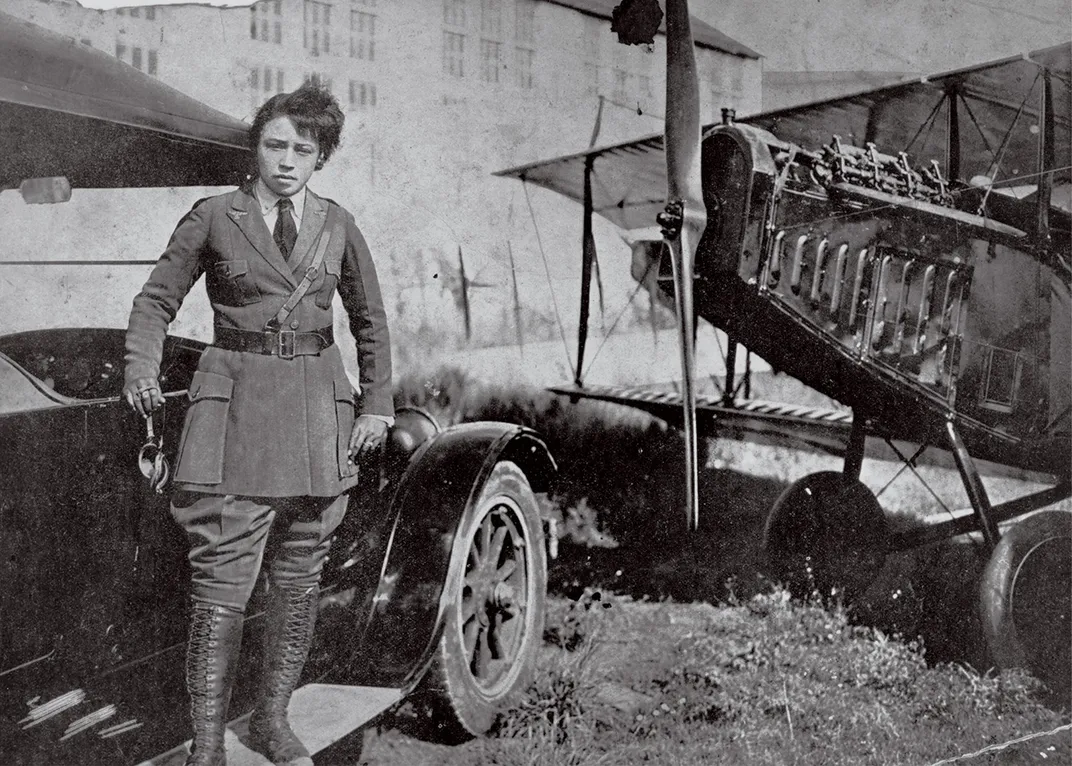 Bessie Coleman stands next to her airplane in uniform