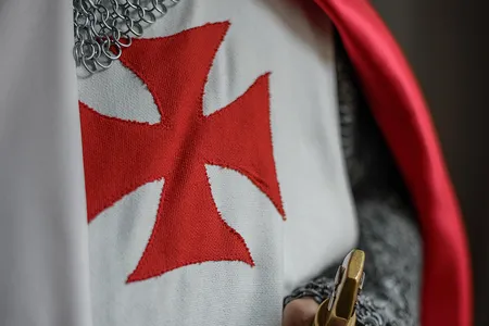 Knights of the SMOTJ wear the red cross pattée, believed to have been first used by the Knights Templar in 1147.