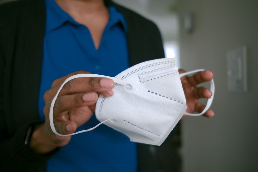 A Black woman holding an N95 face mask in her hands