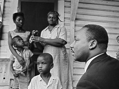 Dr. Martin Luther King Jr. chats with African-Americans during a door-to-door campaign in 1964.
