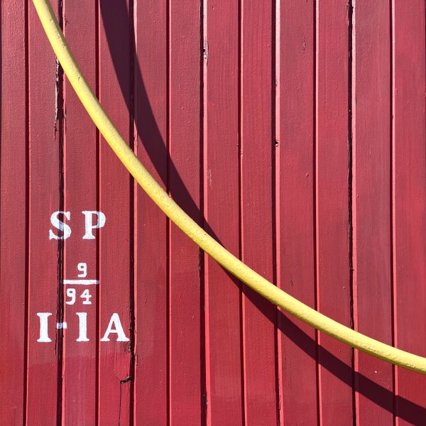 Yellow hose hanging on parked red railroad car. thumbnail