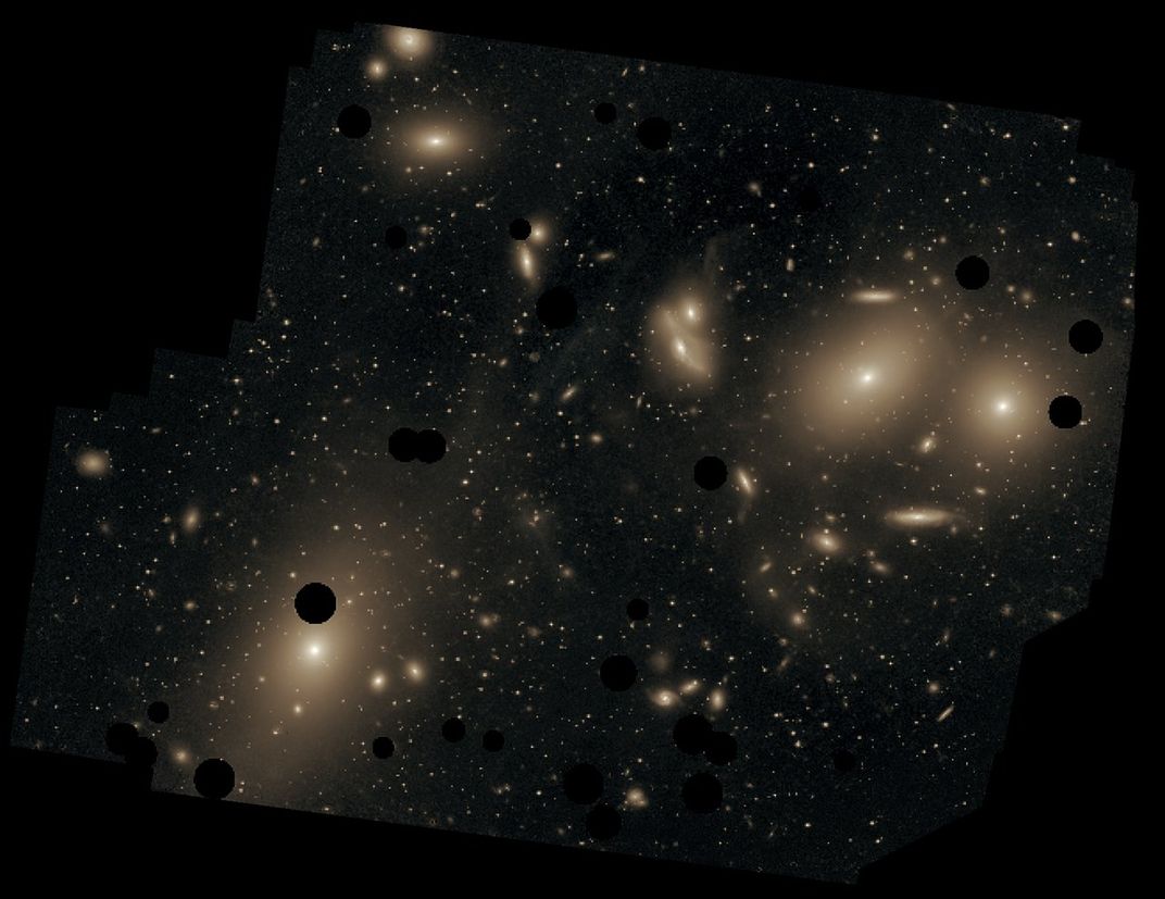a collection of yellow galaxies that appear as fuzzy yellow orbs and ellipses