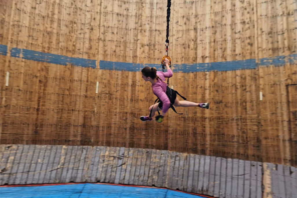 Woman tied to a bungee cord running around a cylindrical wall